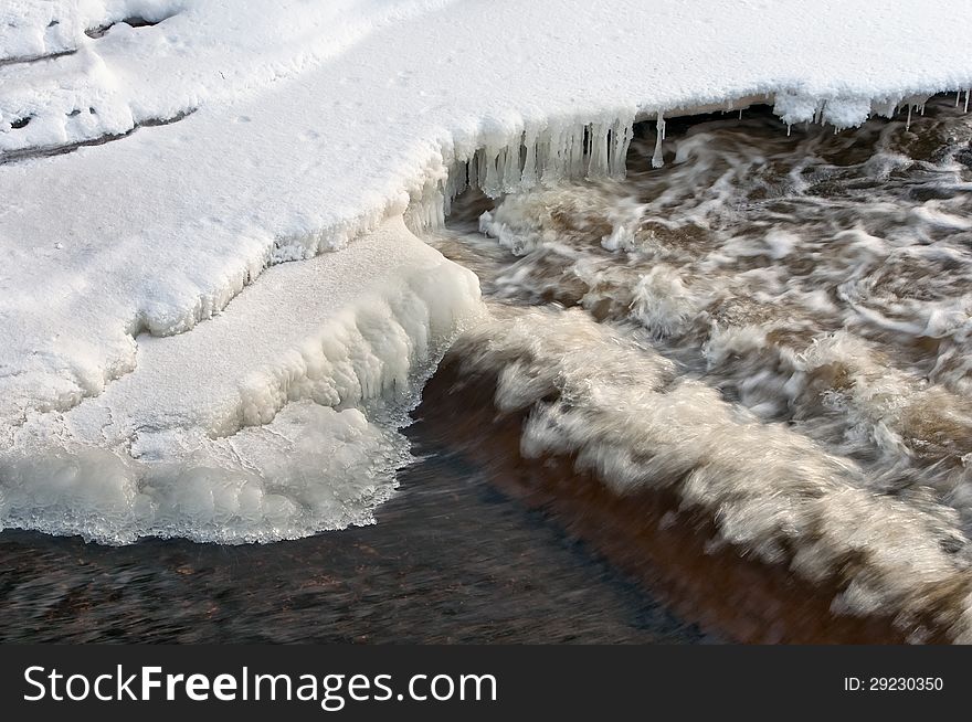 Cascade of icicles hanging over water river