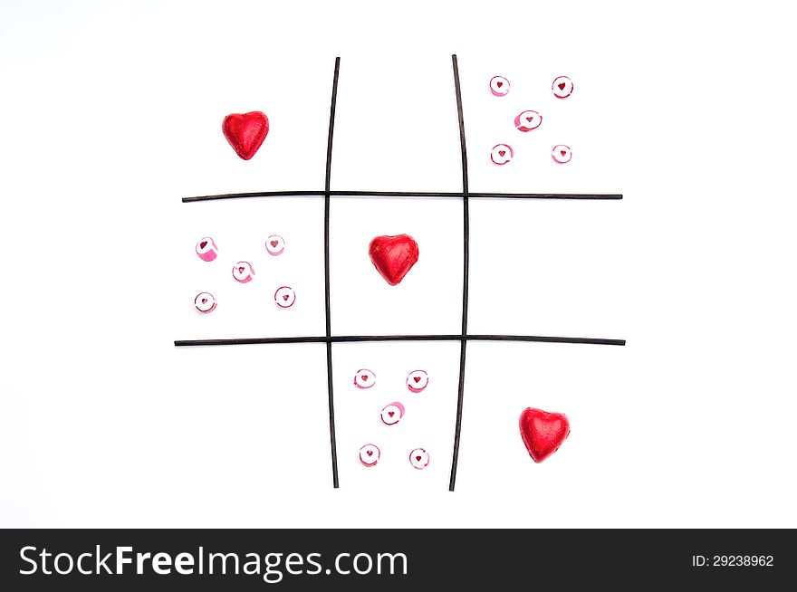 An image representing noughts and crosses with red shaped hearts representing a win and the red candy with hearts in as the opposition. An image representing noughts and crosses with red shaped hearts representing a win and the red candy with hearts in as the opposition