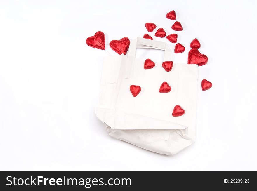 Red hearts scattered on a white paper bag on an isolated white background