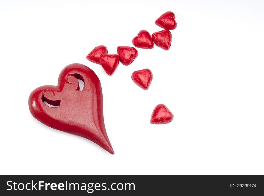 Red wooden heart and smaller chocs on an isolated white background with copy space