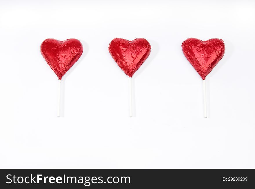 Three red hearts on sticks in a row on an isolated white background