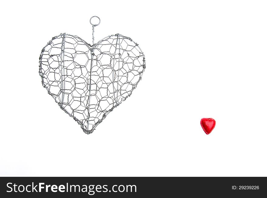 Wire heart shape and a small red hearts on an isolated white background with copy space. Wire heart shape and a small red hearts on an isolated white background with copy space