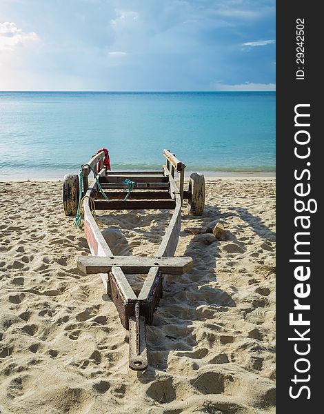 A wooden cart for carry a small boat is on the beach. A wooden cart for carry a small boat is on the beach