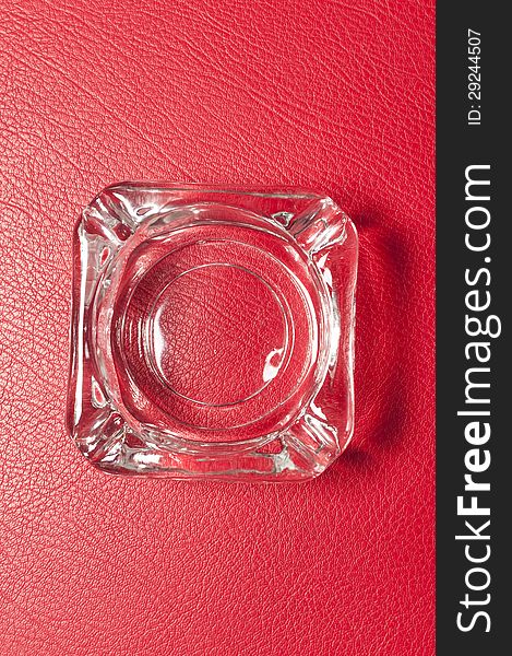 Glass ashtray on red background