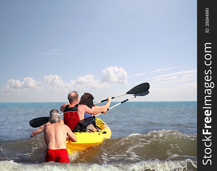 A couple in a canoe trying to cross the first wave with a little help from their friends. A couple in a canoe trying to cross the first wave with a little help from their friends