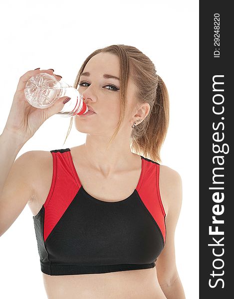 Beautiful happy athletic girl drinking water from a plastic bottle against white background.Healthy lifestyle concept. Beautiful happy athletic girl drinking water from a plastic bottle against white background.Healthy lifestyle concept.