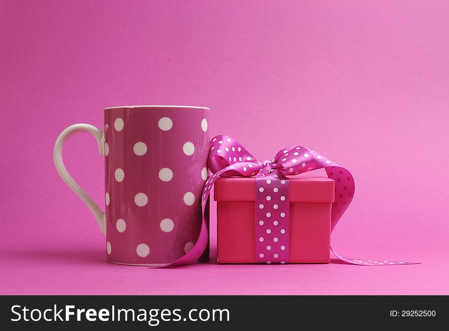 Pretty pink polka dot coffee mug and pink present against a pink background for Valentine, Christmas, Easter, birthday or Mothers Day gift. Pretty pink polka dot coffee mug and pink present against a pink background for Valentine, Christmas, Easter, birthday or Mothers Day gift.