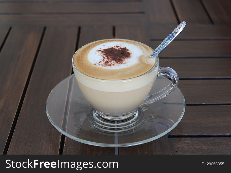 Hot cappuccino in clear mug on table