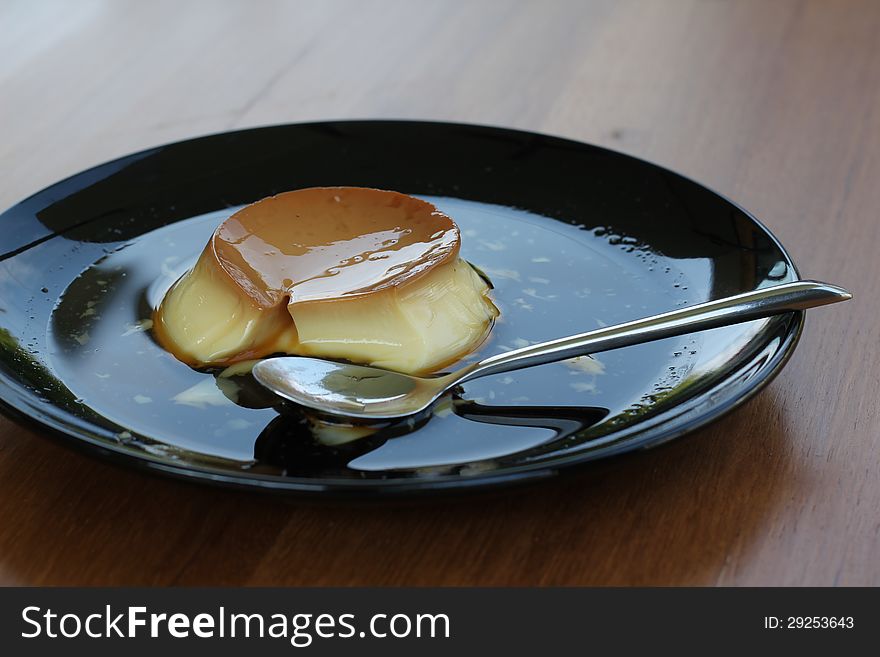 Creme caramel and spoon on black dish