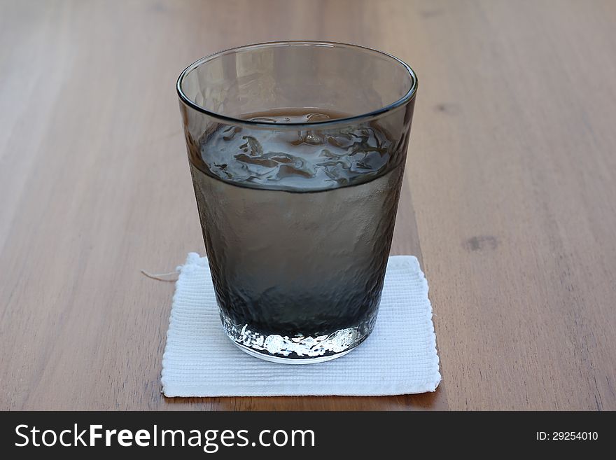 A glass of iced on reflecting table, brown background