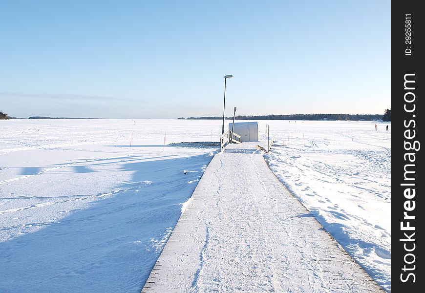 Ice swimming place, pier covered with snow, blue sky