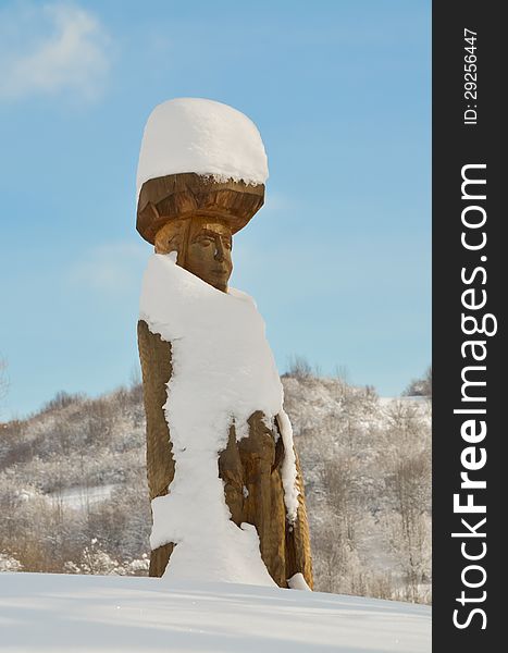 Snow-covered wooden traditional statue. Snow-covered wooden traditional statue