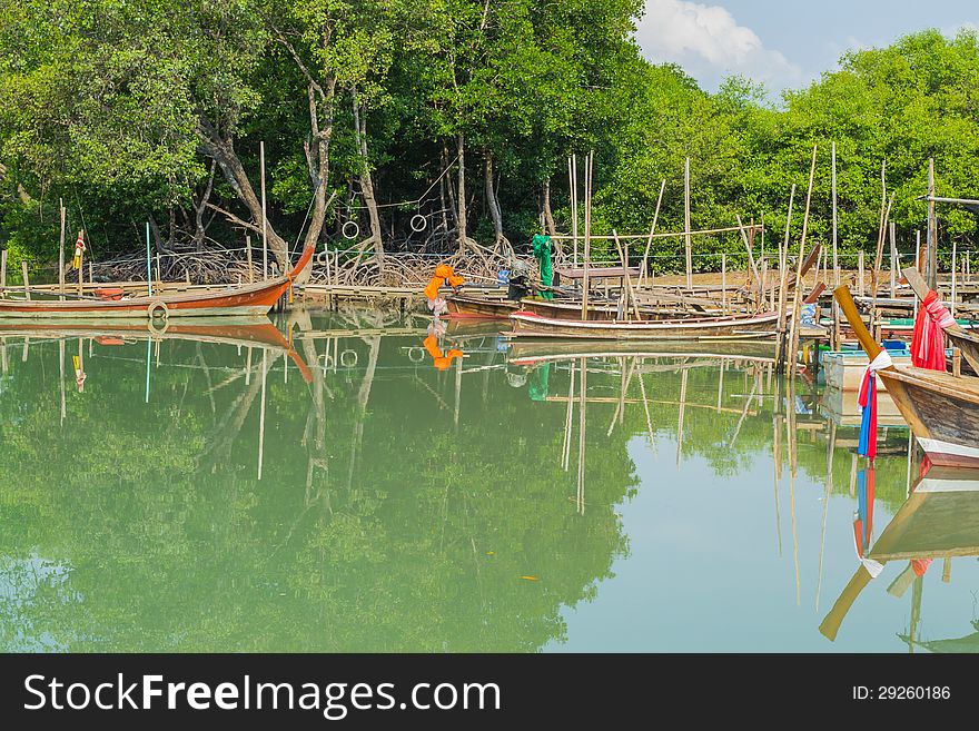 Long tail boats are anchor at the pier among mangrove forest