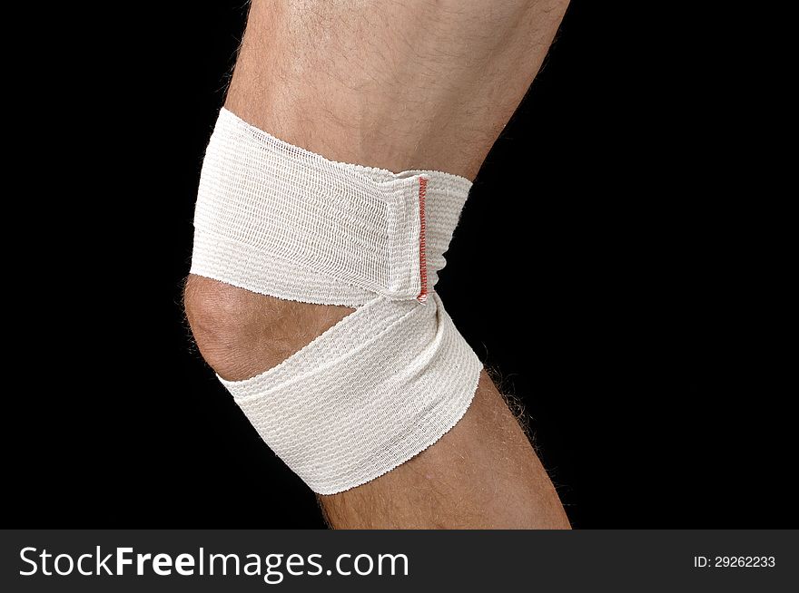 Closeup of male athlete with leg bandaged in sports wrap on black background