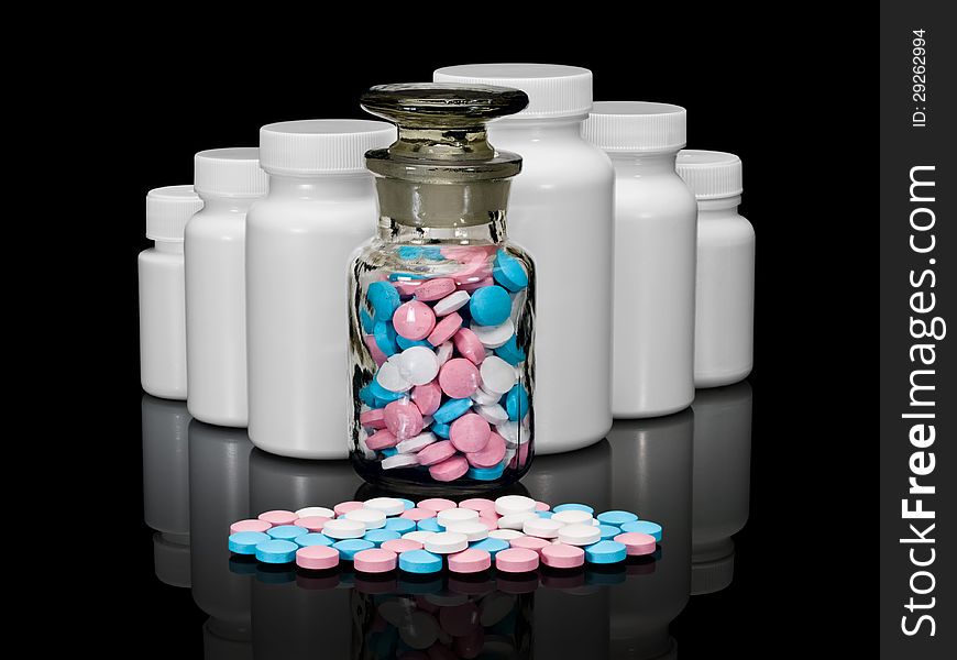 Pills, plastic small bottles and a glass vial on a black background. Pills, plastic small bottles and a glass vial on a black background