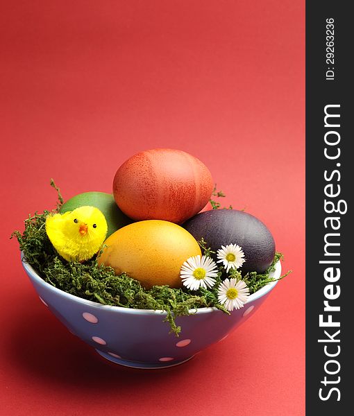 Bright and cheerful Happy Easter still life with rainbow color eggs in orange polka dot bowl against a red background. Bright and cheerful Happy Easter still life with rainbow color eggs in orange polka dot bowl against a red background.