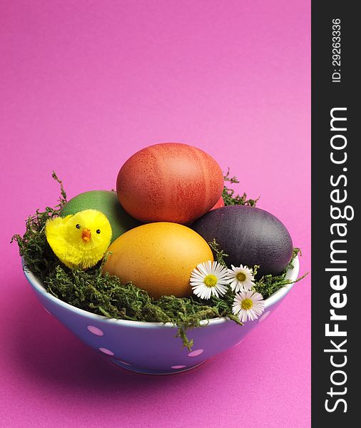 Bright and cheerful Happy Easter still life with rainbow color eggs in orange polka dot bowl against a pink background. Bright and cheerful Happy Easter still life with rainbow color eggs in orange polka dot bowl against a pink background.