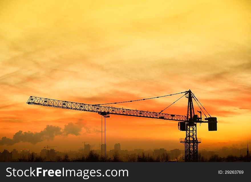 Building crane on background the yellow sky at sunrise. Is view from the heights. Building crane on background the yellow sky at sunrise. Is view from the heights.