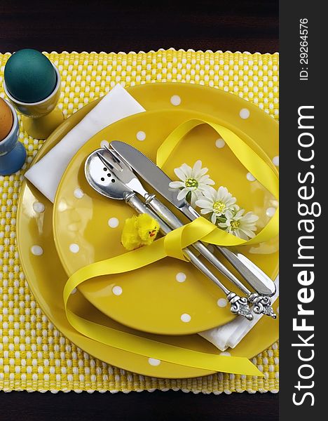 Yellow theme Easter dining table setting with eggs, chick and daisies. Vertical portrait orientation. Yellow theme Easter dining table setting with eggs, chick and daisies. Vertical portrait orientation.