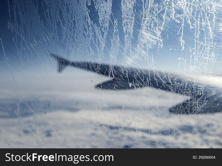 Frosty patterns at a plane window over clouds