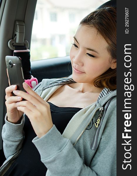 Happy smiling Cute Asian woman using cellphone while sitting in the car. Happy smiling Cute Asian woman using cellphone while sitting in the car.