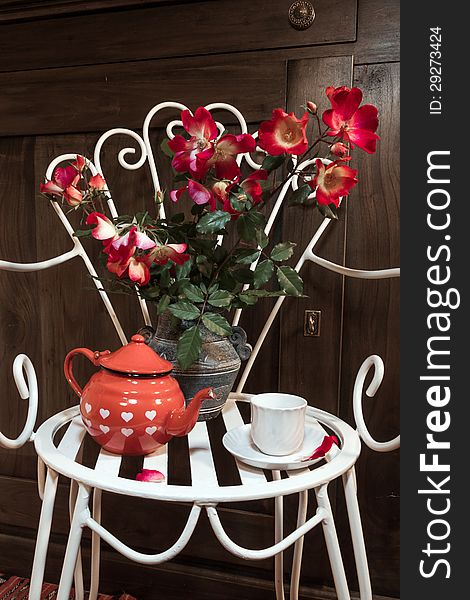 A still life with antique chair, flowers and tea