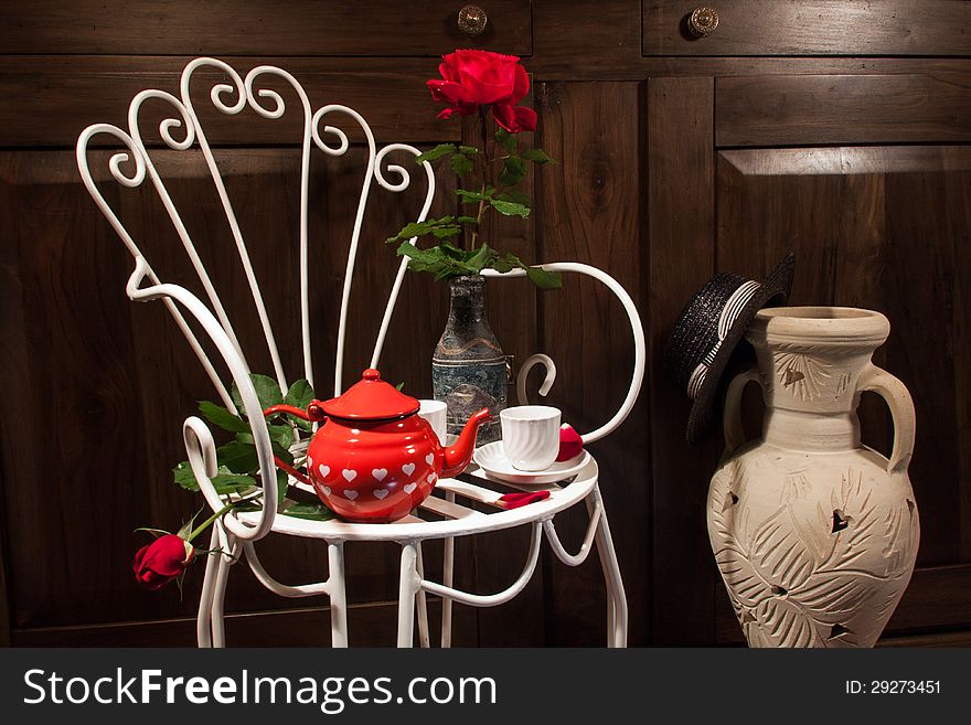A still life with antique chair, flowers and tea