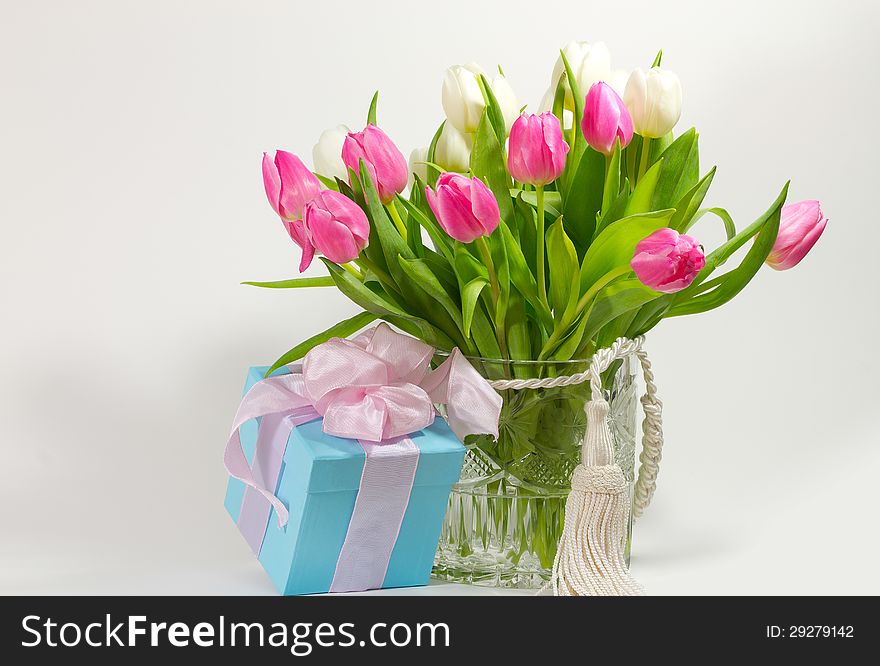 A blue gift parcel next to a spring bouquet with tulips. A blue gift parcel next to a spring bouquet with tulips.