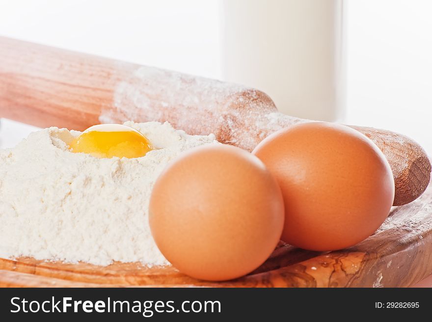 Vintage rolling pin with flour and eggs. Country still life images with soft lighting and small degrees of freedom (selective focus on the yolk)