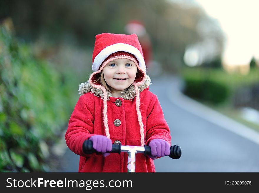 A little girl on a scooter with a Christmas hat. A little girl on a scooter with a Christmas hat.