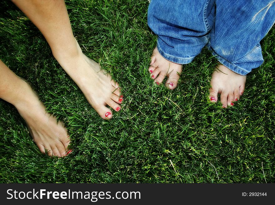 Flower-painted toenails standing on beautiful green grass. Flower-painted toenails standing on beautiful green grass