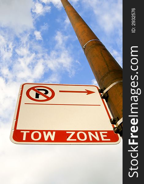 An upward angle of a Tow Zone sign on a pole with the sky in the background.