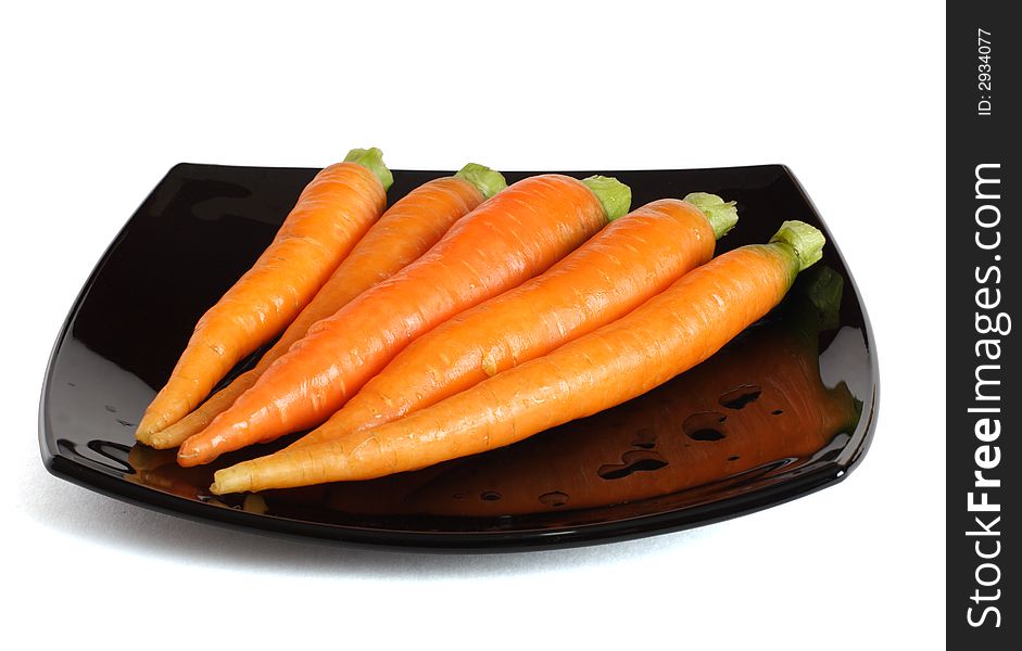 Fresh carrots on a black dish. Isolated. Path.