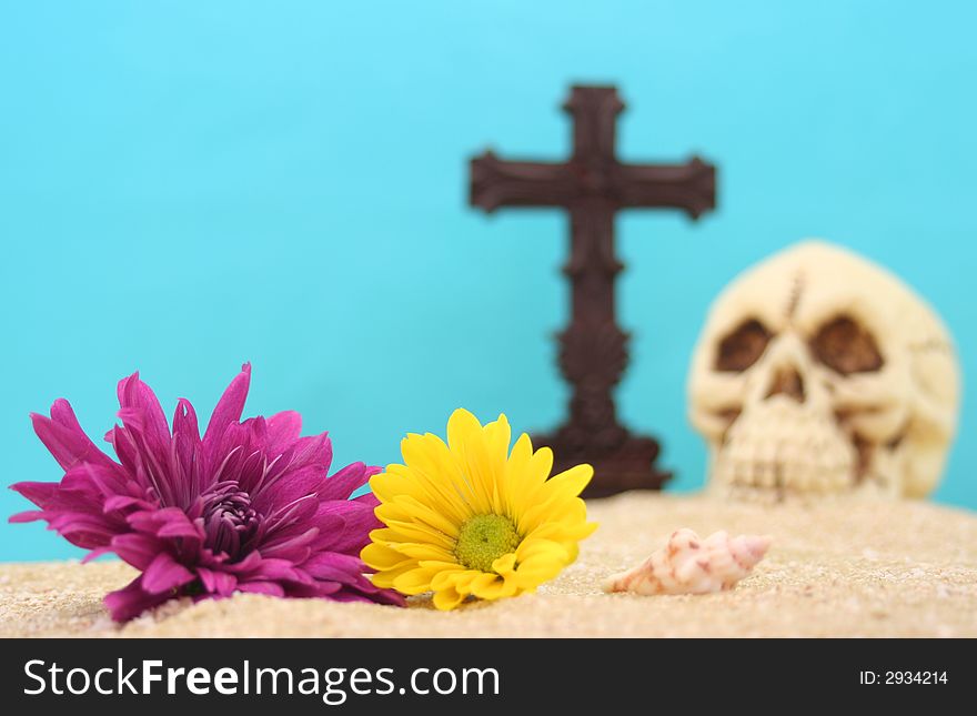 Flowers With Skull and Cross on Sand With Blue Background. Shallow DOF, Focus on Flowers. Flowers With Skull and Cross on Sand With Blue Background. Shallow DOF, Focus on Flowers