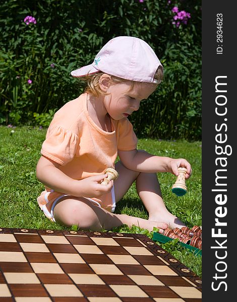 Girl playing chess on lawn