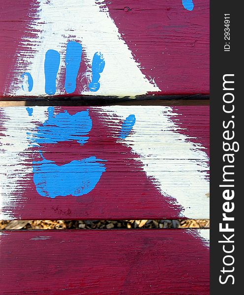 Blue painted hand on red painted picnic table, very fresh bright paint. Blue painted hand on red painted picnic table, very fresh bright paint.