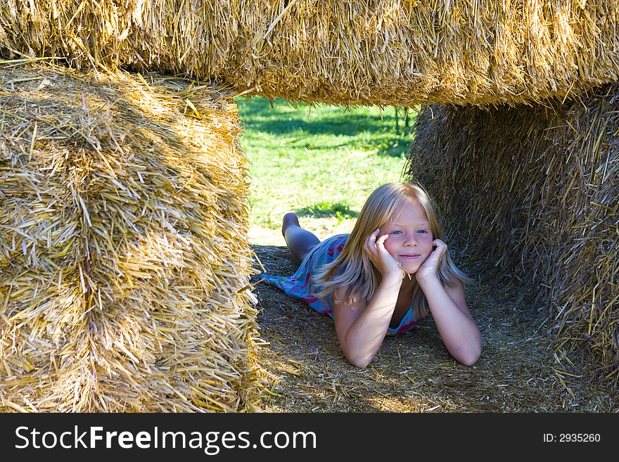 A cute girl relaxing on haybales in a barn. A cute girl relaxing on haybales in a barn