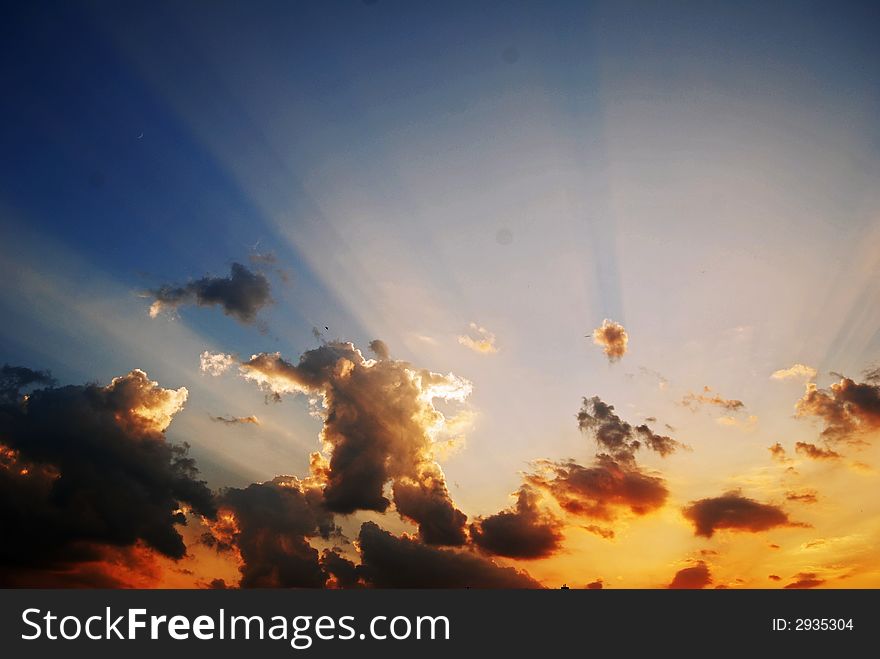 Sunset sky with clouds and light from the sun, blue and yellow-orange sky