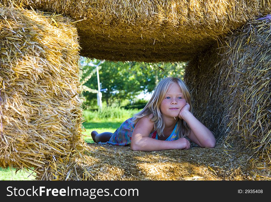 A cute girl relaxing on haybales in a barn. A cute girl relaxing on haybales in a barn