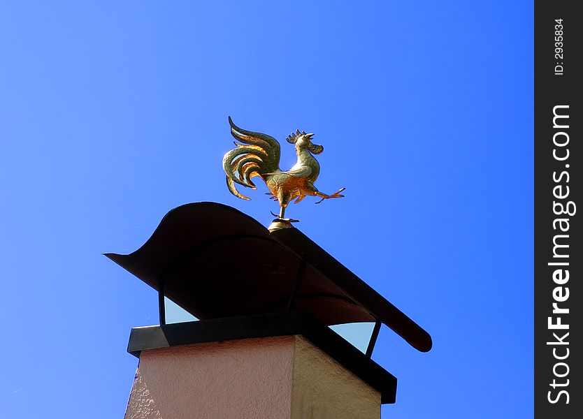 Golden weathercock on a the top of a chimney