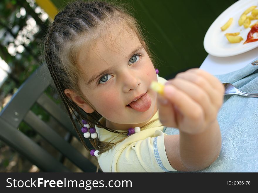 Girl with blue and white plaits eating french potato. Girl with blue and white plaits eating french potato