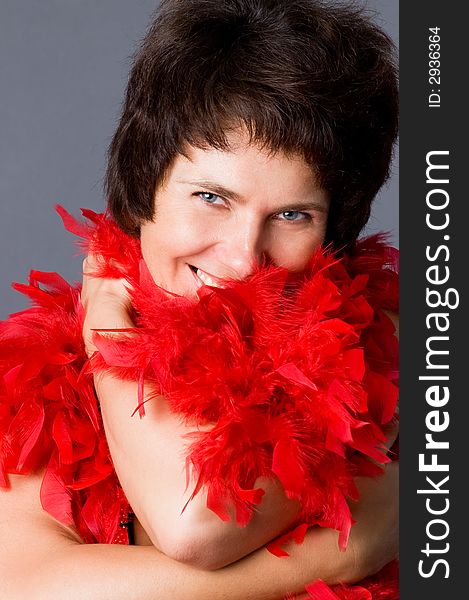 The attractive woman in a red boa, on a grey background. The attractive woman in a red boa, on a grey background