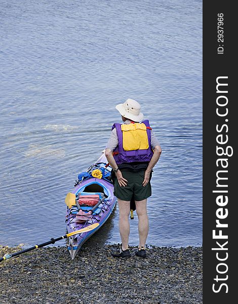 Kayaker observing lake conditions from rocky shoreline