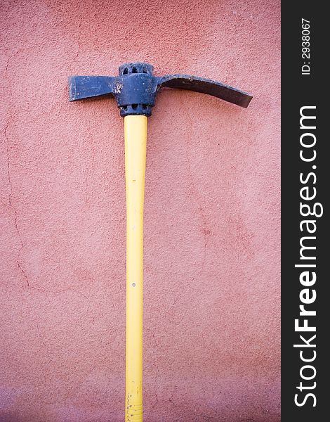 A yellow tool placed against a adobe wall. A yellow tool placed against a adobe wall