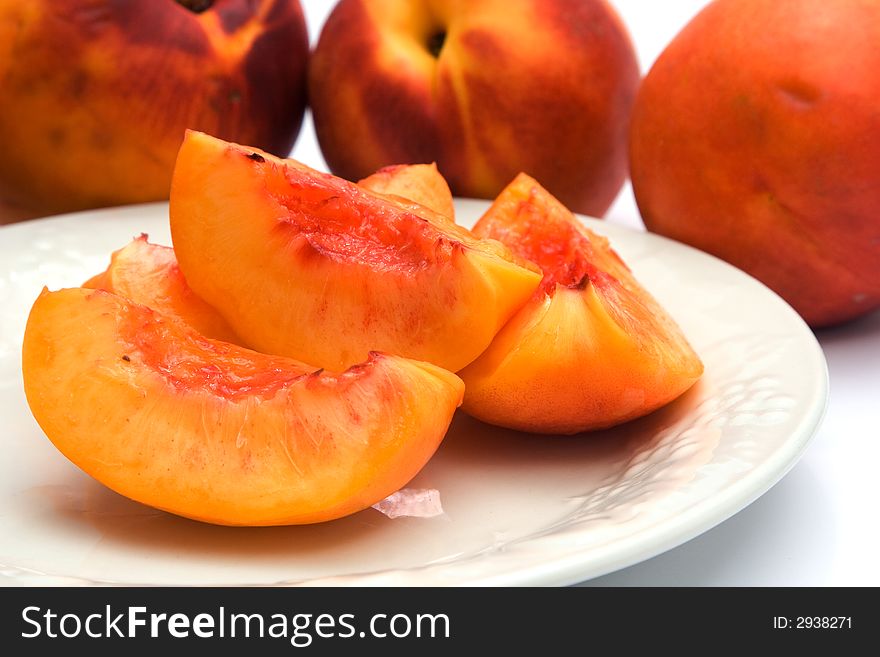Sliced nectarines on a plate with whole nectarines in the background.