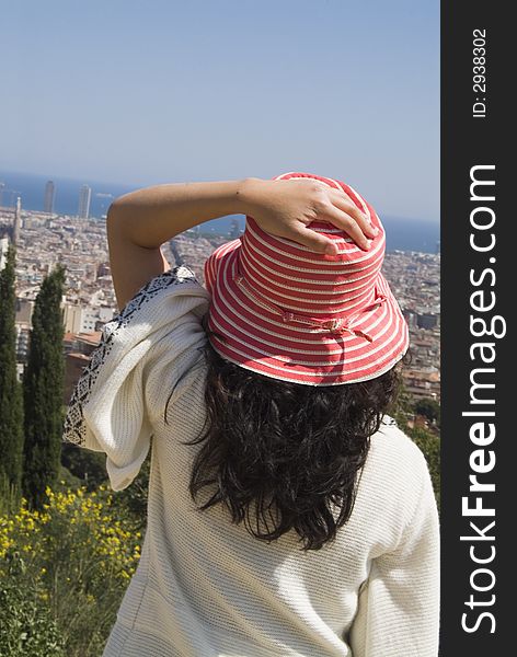 Woman with red and white striped hat over looks a city by the ocean from a mountain. Woman with red and white striped hat over looks a city by the ocean from a mountain.