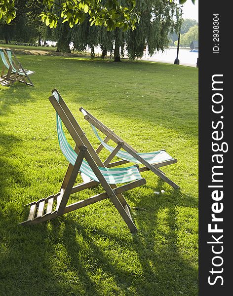 Cyan and white striped folding chairs on a park lawn facing a lake. Cyan and white striped folding chairs on a park lawn facing a lake.