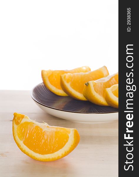 Sliced oranges arranged on a blue striped plate on top of a wooden cutting board. Sliced oranges arranged on a blue striped plate on top of a wooden cutting board.