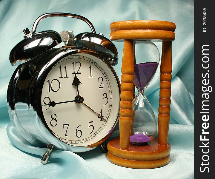 Alarm-clock and sand-glass on blue background minutes. Alarm-clock and sand-glass on blue background minutes