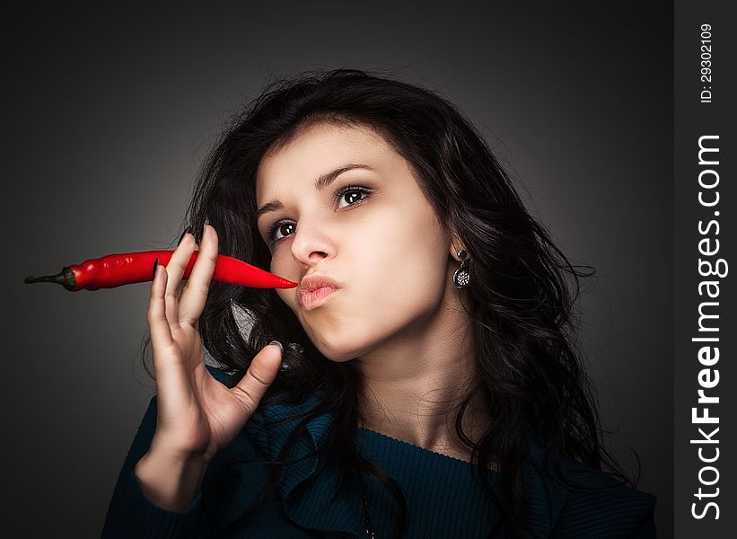Young lady holding red hot chili pepper in mouth. Young lady holding red hot chili pepper in mouth